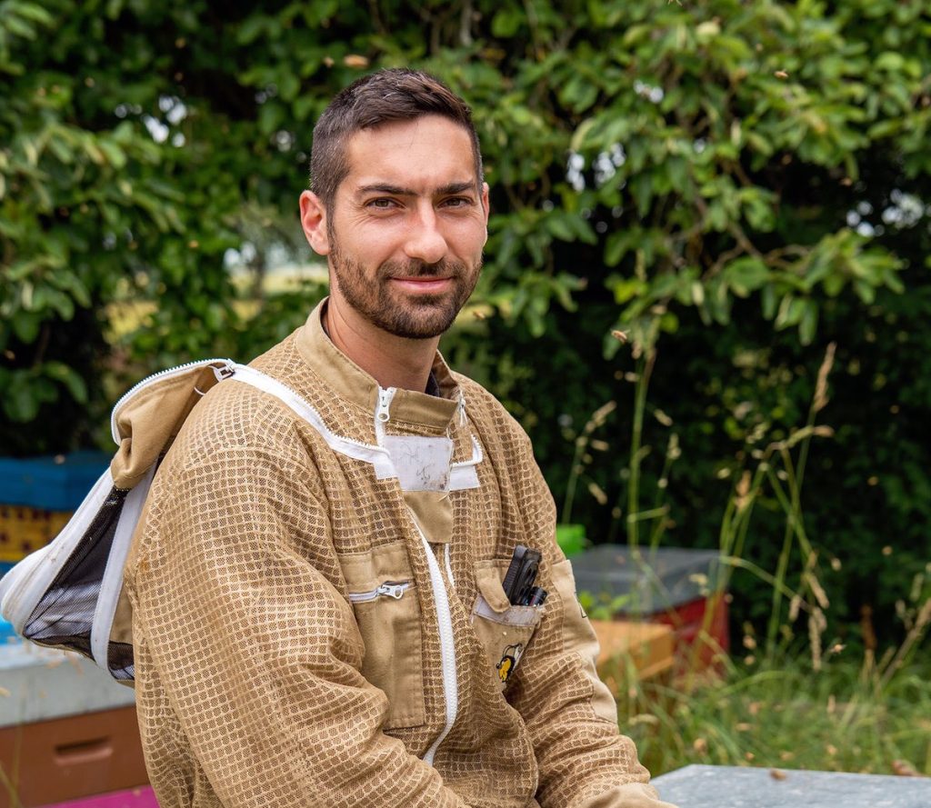 André Mougeot, apiculteur, souriant au milieu de son rucher